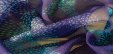 Narin deniz mavisi ve turkuaz noktalı mor bir kumaşın bulanık görüntüsü. Yumuşak kıvrımlar ve karmaşık detaylar sanatsal ve sofistike bir his yaratır..