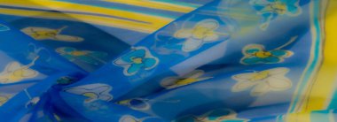 Bulanık çiçek detaylarını sarı ve beyazla süslemek mavi kumaşı hafif ve havadar bir estetik yaratarak parlak ve neşeli bir hava yaratıyor..