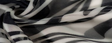Görüntü, koyu dalgalı desenli siyah beyaz kumaş. Dinamik tasarımı ve yumuşak kıvrımları dekorasyon ve moda için modern, sanatsal bir ortam oluşturuyor..