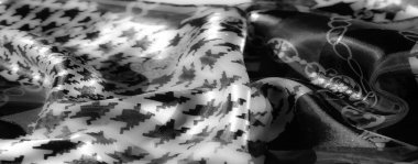 Alternatif çiçek zinciri ve gri tonda geometrik houndstooth motifleri olan bir kumaşın bulanıklığı geleneksel ve soyut tasarımın uyumlu bir karışımını oluşturuyor..