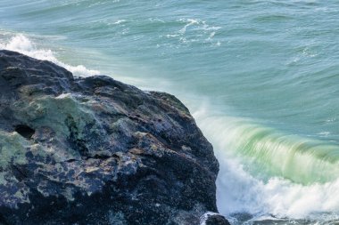 Okyanusun dizginlenemez gücü ve güzelliği yakın planda dalgalar kayalık kıyıya çarpar. Kayaların kaba dokusu, suyun akışkanlığıyla çelişiyor. Huşu hissi uyandırıyor ve merak uyandırıyor..