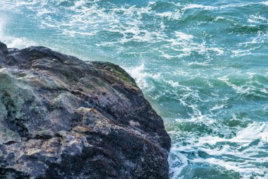 Okyanusun dizginlenemez gücü ve güzelliği yakın planda dalgalar kayalık kıyıya çarpar. Kayaların kaba dokusu, suyun akışkanlığıyla çelişiyor. Huşu hissi uyandırıyor ve merak uyandırıyor..