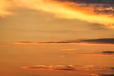 Güneşle boyanmış güzel bir gökyüzü ardında parlak altın tonları bırakır. Pembe, mavi ve çok renkli. Alacakaranlık gökyüzünde bulutlar, akşam. Akşamları bulutlu bir gökyüzünün görüntüsü. Akşam gökyüzü sahnesi Altın ışıkla