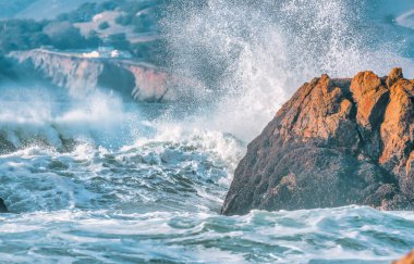 Dalga yakın planda sıçrıyor. Kristal berrak deniz suyu okyanusta, San Francisco Körfezi 'nde kaya oluşumlarına çarpar. Mavi su, pastel renkler..