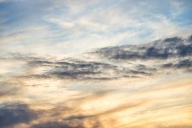 Güneşle boyanmış güzel bir gökyüzü ardında parlak altın tonları bırakır. Pembe, mavi ve çok renkli. Alacakaranlık gökyüzünde bulutlar, akşam. Akşamları bulutlu bir gökyüzünün görüntüsü. Akşam gökyüzü sahnesi Altın ışıkla