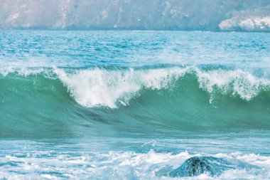 Dalga yakın planda sıçrıyor. Kristal berrak deniz suyu okyanusta, San Francisco Körfezi 'nde kaya oluşumlarına çarpar. Mavi su, pastel renkler..