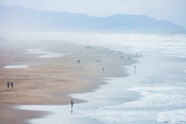 Sisteki güzel manzara manzarası, Ocean Beach San Francisco boyunca yürüyen insanlar. Pasifik Okyanusu.