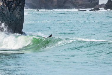 San Francisco, California, ABD - 23 Ekim 2021, San Francisco 'da bir sörfçü arka planda kayalıklarla dalgalar sürüyor.