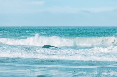 Dalga yakın planda sıçrıyor. Kristal berrak deniz suyu okyanusta, San Francisco Körfezi 'nde kaya oluşumlarına çarpar. Mavi su, pastel renkler..