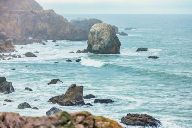 Okyanusun ham gücü ve güzelliği, yakın çekim, kayalık deniz kayalıkları, Pasifik Körfezi 'nin güzel dramatik deniz manzarası, Kaliforniya, ABD. Kayaların kaba dokusu, suyun akışkanlığıyla çelişiyor. Huşu hissi uyandırıyor ve merak uyandırıyor..