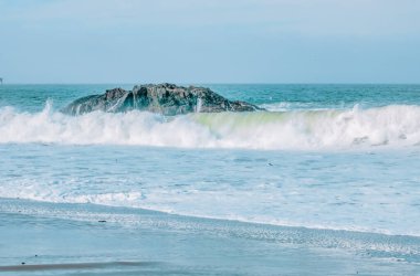 Dalga yakın planda sıçrıyor. Kristal berrak deniz suyu okyanusta, San Francisco Körfezi 'nde kaya oluşumlarına çarpar. Mavi su, pastel renkler..