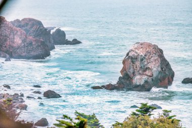Okyanusun ham gücü ve güzelliği, yakın çekim, kayalık deniz kayalıkları, Pasifik Körfezi 'nin güzel dramatik deniz manzarası, Kaliforniya, ABD. Kayaların kaba dokusu, suyun akışkanlığıyla çelişiyor. Huşu hissi uyandırıyor ve merak uyandırıyor..