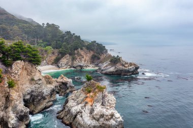 1. Otoyol ve Big Sur boyunca Pasifik Okyanusu 'nun güzel manzarası, yukarıdan McWay Falls manzarası, gün batımı, gün doğumu, sis. Kavram, seyahat, tatil, hafta sonu.