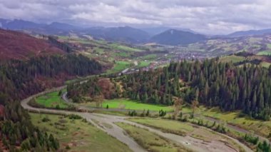 4k video. Yazın güneşli bir günde dağlarda çayırları ve çayırları olan yeşil bir orman. Karpat dağlarının güzel doğası, Batı Ukrayna, Avrupa. Hava aracı güzel dağlardaki manzarayı görüntüledi.