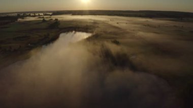 Havadan güzel büyülü manzara ufku, insansız hava aracı üstgeçişi, sisli, bulut tarlası gölü ve ormandaki gündoğumunun altın panoramik manzarası. 4K video