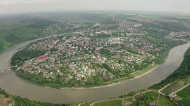 4K video, hava manzarası, Zalishyky şehrinin güzel manzarası. At nalı şeklinde kıvrımlı bir nehir ve üzerinde bir köprü. Orman, bitki örtüsü ve binaları olan bir vadi. Ufuk ve gökyüzü hafif sisli