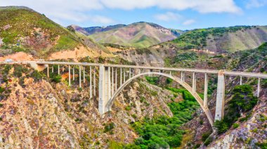 Kaliforniya Otoyolu 1 'deki Bixby Creek Köprüsü' nün çarpıcı manzarası. Köprü, pitoresk uçurumların ve turkuaz Pasifik sularının üzerine uzanarak eşsiz bir manzara ve seyahat atmosferi yaratır..