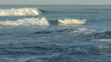 Okyanus arka planı, parlak mavi gökyüzü beyaz bulutlar ve açık denizde dalgalar ufka yaklaşıyor.
