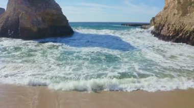 Güneş doğarken güzel bir sahile vuran okyanus dalgalarını kapat.