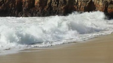 Güneş doğarken güzel bir sahile vuran okyanus dalgalarını kapat.