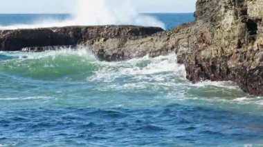 Güneş doğarken okyanus dalgaları kayalara çarpıyor.