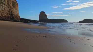 Kumsalda altın gün batımı, köpüklü dalgalar beyaz kumsala doğru yuvarlanıyor güneş ışığı altında