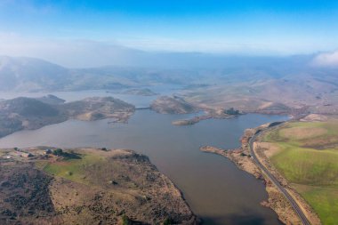 Kaliforniya 'nın yuvarlanan tepeleri ve doğal manzaralarıyla çevrili çarpıcı bir göl manzarası. Doğa meraklıları, fotoğrafçılar ve gezginler için mükemmel bir doğa harikası.