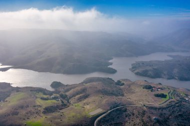 Kaliforniya 'nın yuvarlanan tepeleri ve doğal manzaralarıyla çevrili çarpıcı bir göl manzarası. Doğa meraklıları, fotoğrafçılar ve gezginler için mükemmel bir doğa harikası.