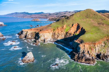 Kaliforniya 'nın Kuzey Kaliforniya Otoyolu boyunca uzanan sahil kayalıkları. Engebeli okyanus kayaları, çarpan dalgalar ve renkli bir gökyüzü nefes kesici bir Pasifik Sahili manzarası yaratır..