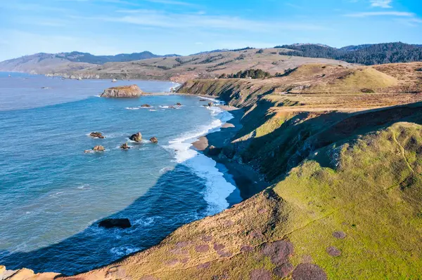 Kaliforniya 'nın Kuzey Kaliforniya Otoyolu boyunca uzanan sahil kayalıkları. Engebeli okyanus kayaları, çarpan dalgalar ve renkli bir gökyüzü nefes kesici bir Pasifik Sahili manzarası yaratır..