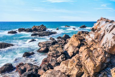 Kaliforniya 'nın Kuzey Kaliforniya Otoyolu boyunca uzanan sahil kayalıkları. Engebeli okyanus kayaları, çarpan dalgalar ve renkli bir gökyüzü nefes kesici bir Pasifik Sahili manzarası yaratır..
