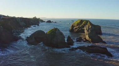 Kuzey Kaliforniya 'daki California Otoyolu boyunca uzanan sahil kayalıkları. Engebeli okyanus kayaları, çarpan dalgalar ve renkli bir gökyüzü nefes kesici bir Pasifik Sahili manzarası yaratır..