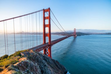 Golden Gate Köprüsü, San Francisco, California 'da gün doğumunda. Yumuşak pastel gökyüzü, sakin körfez suları ve ikonik kırmızı mimarisi olan Battery Spencer 'dan manzara. Huzurlu seyahat manzarası.
