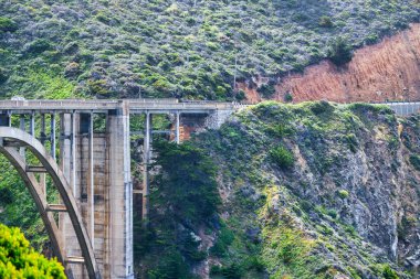 Bixby Creek Köprüsü Big Sur, California 'daki 1. Otoyol boyunca. Pasifik kıyısındaki engebeli kayalıkların, turkuaz dalgaların ve ikonik kıyı mühendisliğinin dramatik bir görüntüsü.