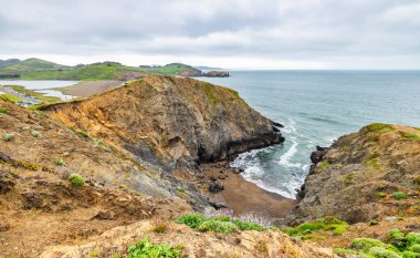 Marin Headlands, Kaliforniya 'daki Rodeo Sahili Sahil Yolu' ndan manzara, engebeli uçurumları, gizli sahil koylarını ve San Francisco yakınlarında bulutlu gökyüzünün altında Pasifik Okyanusu 'nu gösteriyor.