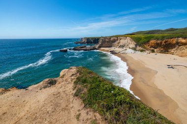 California 'daki Panther Sahili' nde turkuaz dalgalar, altın kum ve dramatik uçurumlar var. Açık bir bahar gününde yukarıdan görüldü.