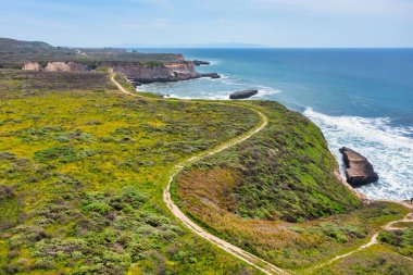 Kaliforniya, Davenport yakınlarındaki dramatik deniz kayalıkları boyunca kıyı şeridi kıvrımları var. Havadan bakıldığında, turkuaz üzerinde doğal bir kaya kemeri görünüyor. Pasifik kıyısındaki ikonik otoyol boyunca dalgalar var..