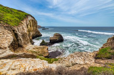 Kaliforniya, Davenport yakınlarındaki sahili ve okyanus dalgalarını. Engebeli kaya oluşumları, Pasifik kıyısı boyunca turkuaz suların üzerinde yükseliyor ve patikadan nefes kesici bir manzara sunuyor.