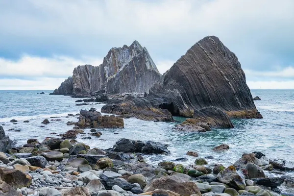 Pasifik, Kaliforniya yakınlarındaki San Pedro Kayası 'nın yakın görüntüsü. Okyanustan yükselen katmanlı volkanik oluşumlar, dramatik bulutlu bir gökyüzünün altında gelgitler ve kayalık kıyılarla çevrili.