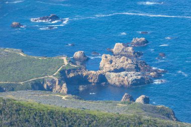 Kaliforniya, Garrapata Eyalet Parkı 'ndaki Soberanes Kanyonu yakınlarındaki 1. Otoyol boyunca uzanan engebeli kıyı şeridi ve okyanus kayalıkları. Derin mavi sular ve dramatik kayalar doğal güzelliği vurgular.