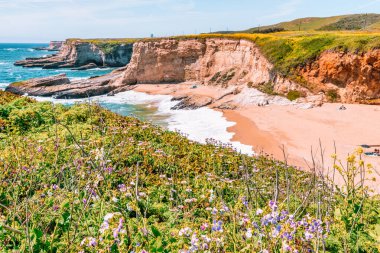 California 'daki Panther Sahili' nde turkuaz dalgalar, altın kum ve dramatik uçurumlar var. Açık bir bahar gününde yukarıdan görüldü.