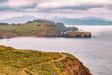 San Francisco, Kaliforniya yakınlarındaki Pasifik Okyanusu ve dramatik sahil uçurumlarına bakan Marin Burunlarının yemyeşil tepelerini saran dolambaçlı bir patika kesiyor.