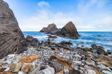 Pasifik, Kaliforniya yakınlarındaki San Pedro Kayası 'nın yakın görüntüsü. Okyanustan yükselen katmanlı volkanik oluşumlar, dramatik bulutlu bir gökyüzünün altında gelgitler ve kayalık kıyılarla çevrili.