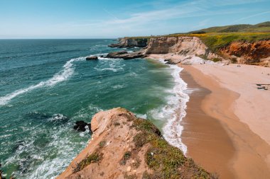 California 'daki Panther Sahili' nde turkuaz dalgalar, altın kum ve dramatik uçurumlar var. Açık bir bahar gününde yukarıdan görüldü.