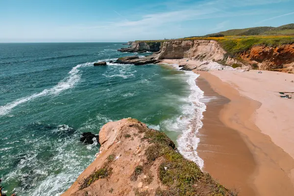 California 'daki Panther Sahili' nde turkuaz dalgalar, altın kum ve dramatik uçurumlar var. Açık bir bahar gününde yukarıdan görüldü.
