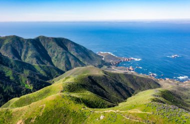 Green Ridges ve Soberanes Canyon Trailhead 'deki Pasifik kıyı şeridi, Büyük Sur, 1. Otoyol yakınlarında. Açık mavi gökyüzünün altında okyanusa yuvarlanan tepelerden oluşan manzaralı bir manzara.
