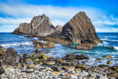 Pasifik, Kaliforniya yakınlarındaki San Pedro Kayası 'nın yakın görüntüsü. Okyanustan yükselen katmanlı volkanik oluşumlar, dramatik bulutlu bir gökyüzünün altında gelgitler ve kayalık kıyılarla çevrili.