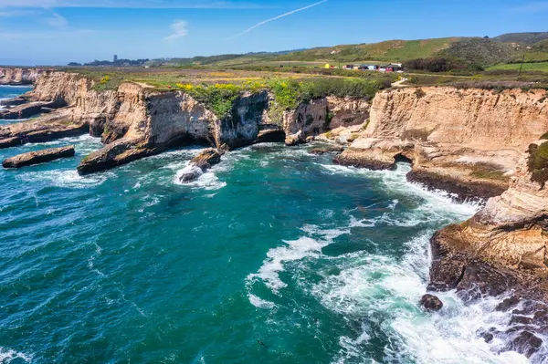Cotoni-Coast Mandıra Eyalet Plajları 'ndaki Panther Plajı, Kaliforniya. Altın kum, dramatik uçurumlar, turkuaz dalgalar ve 1. Otoyol 'un yanındaki parlak mavi gökyüzünün altındaki manzaralı kıyı şeridi.
