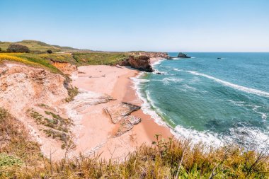 California 'daki Panther Sahili' nde turkuaz dalgalar, altın kum ve dramatik uçurumlar var. Açık bir bahar gününde yukarıdan görüldü.