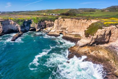 Cotoni-Coast Mandıra Eyalet Plajları 'ndaki Panther Plajı, Kaliforniya. Altın kum, dramatik uçurumlar, turkuaz dalgalar ve 1. Otoyol 'un yanındaki parlak mavi gökyüzünün altındaki manzaralı kıyı şeridi.